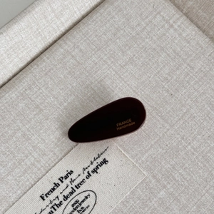 Detail of a dark reddish-brown acetate hair clip with France Handmade engraving