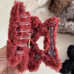 Detail shot of plush red star hair claw clip with fuzzy texture and metal spring