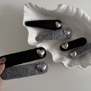 Detail view of heart-shaped hair clips in black plush and silver glitter fabric finish