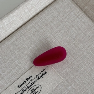Macro detail of magenta acetate hair clip with FRANCE handmade engraving on linen