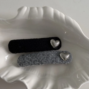 Detail view of black and grey fabric hair clips with silver heart metal accents