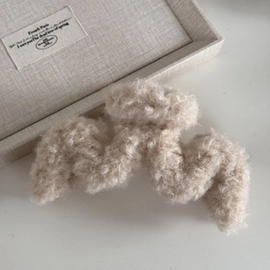 Dettaglio della molletta per capelli in morbido sherpa crema con design a onde