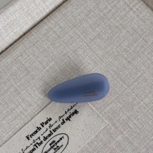 Detail view of a matte blue teardrop acetate hair clip featuring France handmade lettering