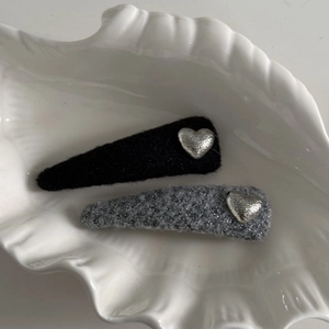 Detailed view of black velvet and grey glitter fabric hair clips with silver heart charms