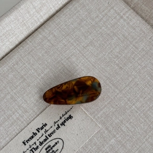 Detail of tortoiseshell acetate hair clip with elegant waterdrop shape on rustic fabric