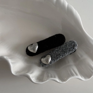Detail view of retro fabric BB hair clips with textured silver heart accents in a shell dish