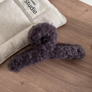 Gros plan détaillé de la pince à cheveux en peluche violet foncé sur une surface en bois