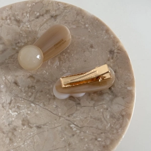 Detailed macro view of resin heart hair clips with golden alligator fasteners on marble