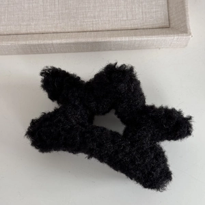 Close-up of black star-shaped plush hair claw clip featuring soft faux lamb wool texture