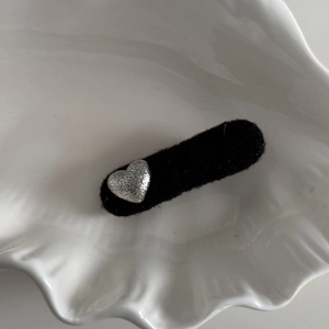 Close-up of black velvet hair clip with silver textured heart detail in a shell tray