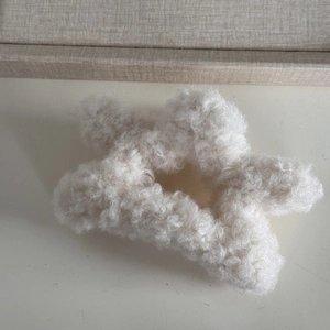 Close-up of white plush star-shaped hair claw clip made of soft faux lamb wool material