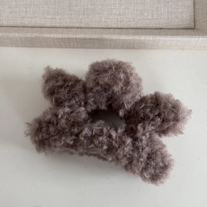 Detailed close-up of a soft faux fur star-shaped hair claw clip in a neutral taupe shade