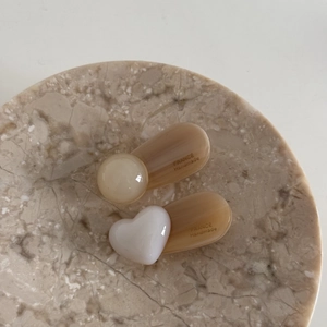 Detailed macro view of cream heart and bead hair clips on a marble tray