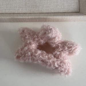 Close-up of a pink plush star hair claw clip with soft faux lamb wool texture detail