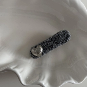 Detailed macro view of charcoal grey tweed hair clip with a vintage matte silver heart accent