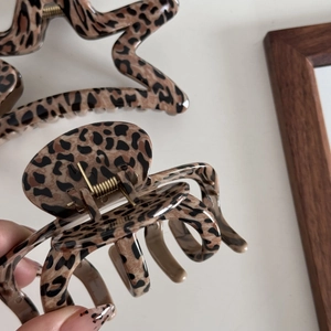 Detailed view of leopard print hair claws in star and oval shapes with metal springs