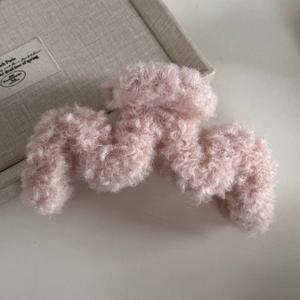 Dettaglio della pinza per capelli in lana d'agnello rosa con una morbida trama di peluche