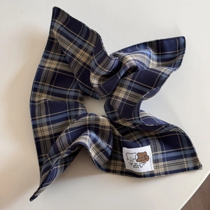 Detail of navy blue plaid scrunchie featuring a white cartoon bear fabric label