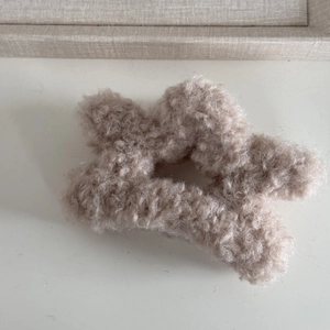 Macro shot of a star-shaped plush hair claw clip in soft beige faux lamb wool fabric