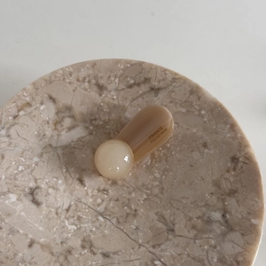 Detailed view of handmade acetate hair clip with beige heart shape on marble tray