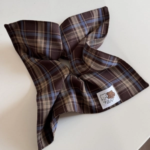 Close-up of plaid scrunchie fabric with a cute bear tag and motivational text detail