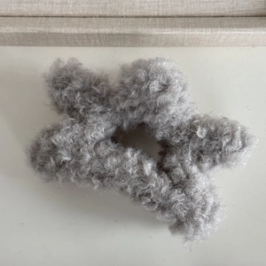 Detail of plush grey star-shaped hair claw clip with soft faux sherpa lamb wool texture