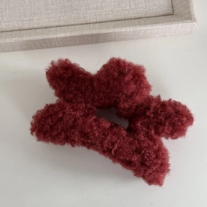 Close-up of deep red star hair claw clip with cozy plush lamb wool texture detail