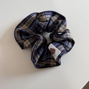Detail of blue plaid fabric hair scrunchie featuring a cute cartoon bear patch
