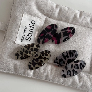 Lot de six barrettes ovales à motif léopard en rose, marron et gris sur un support en lin