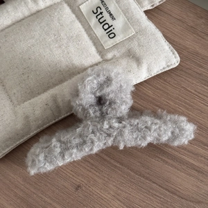 Gros plan sur une pince à cheveux en peluche grise douce avec une texture bouclée