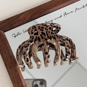 Macro detail of high-gloss leopard print hair claw clip on mirror with strong grip teeth