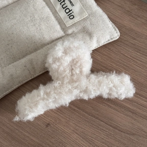 Vue détaillée d'une pince à cheveux en laine d'agneau duveteuse avec texture pelucheuse