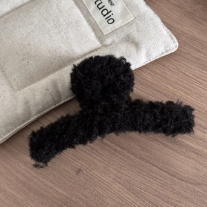 Détail de la texture en polaire noire douce sur une grande pince à cheveux
