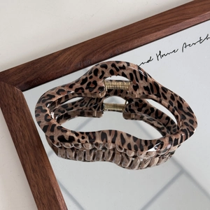 Detail view of large brown leopard print hair claw clip with golden metal spring