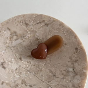 Detailed close-up of brown heart-shaped resin hair clip on marble texture background