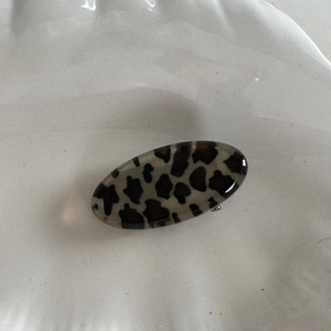 Gros plan sur une pince à cheveux ovale motif léopard avec une finition brillante