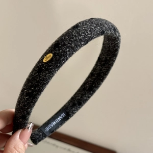Detailed macro view of dark grey tweed headband texture with a golden Love metal badge
