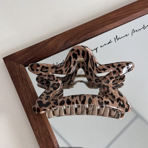 Detail of star-shaped leopard print hair claw clip showing polished resin finish and teeth