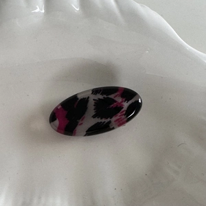 Vue détaillée d'une pince à cheveux ovale en résine avec motif léopard rose sur plateau