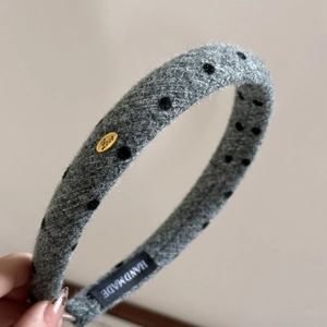 Detail of grey wool headband with black polka dots and gold Love metal emblem