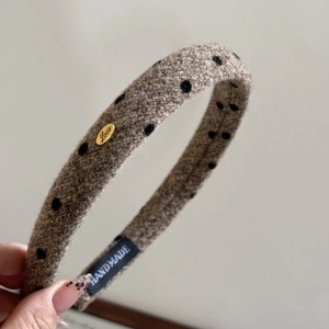 Detailed view of handmade polka dot sponge headband with golden metal brand tag
