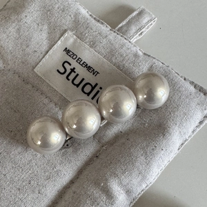 Détail macro de quatre grandes perles brillantes sur une barrette dorée pour femmes