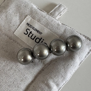 Vue macro d'une barrette à quatre billes métalliques sur un pochon en toile beige