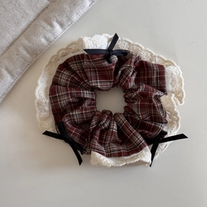 Detail of red plaid scrunchie with white lace edges and black silk bow accents