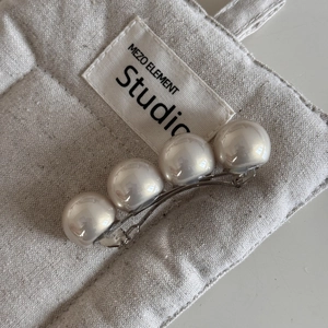 Vue rapprochée de quatre perles crème sur une barrette à cheveux en métal argenté