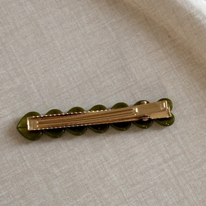 Détail d'une pince à cheveux cœur acétate vert olive avec base dorée en métal