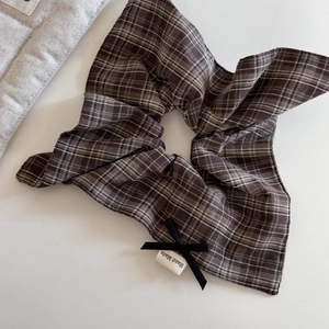 Detail showing the retro plaid fabric hair tie with black bow and Hand Made label