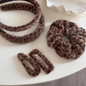Detail view of plush brown leopard print hair set including headband, scrunchie and clips