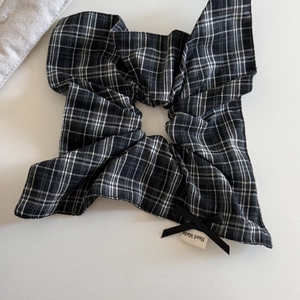 Close-up of black and white plaid scrunchie with a small bow and Hand Made tag