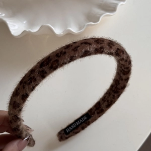 Close-up of leopard print faux fur headband with a handmade label on the inner side